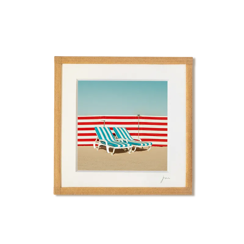 tirage photo petit format encadré à la main représentant deux transats de plage rayé bleus devant un paravent rayé rouge