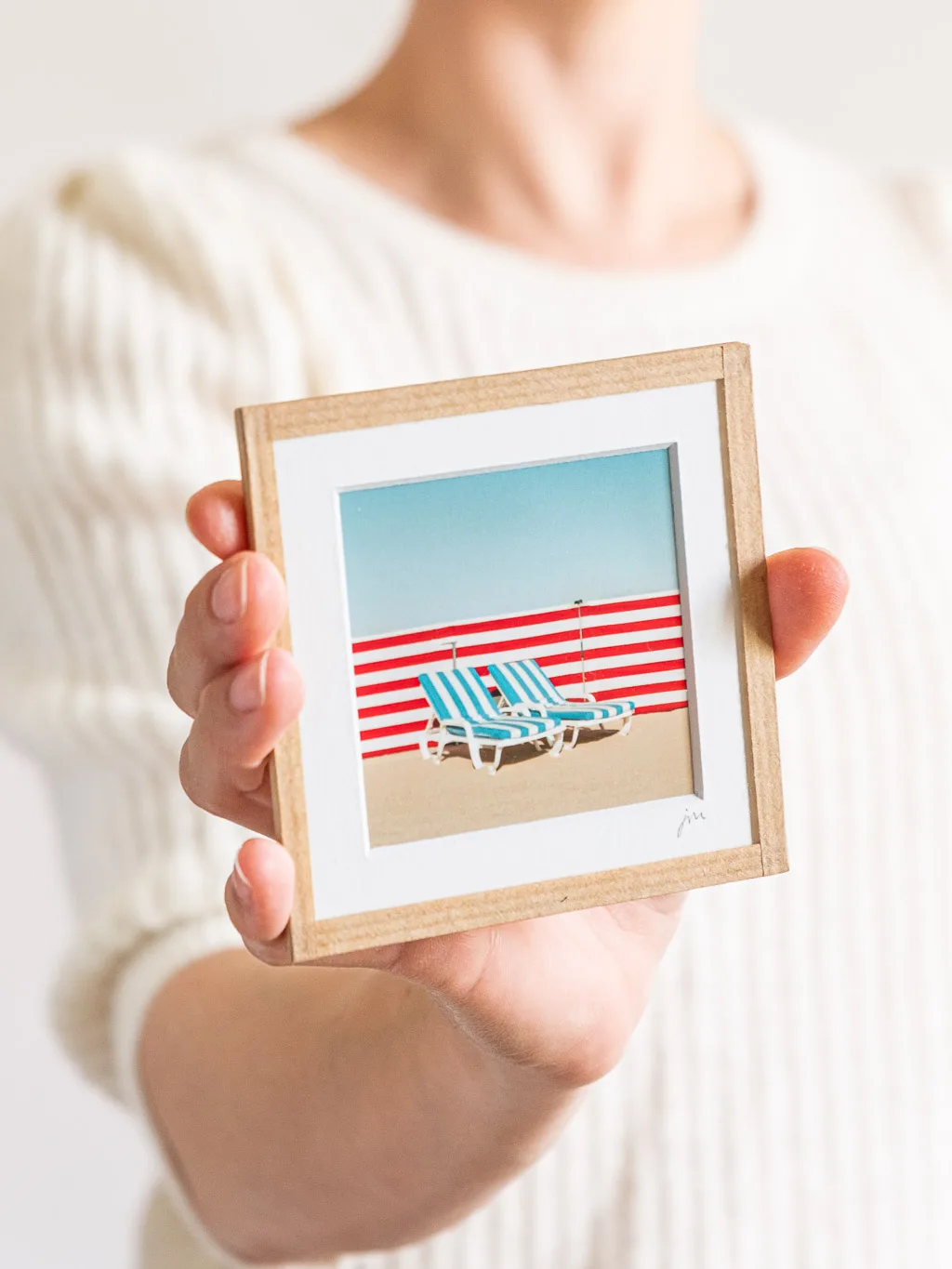 tirage photo petit format encadré à la main représentant deux transats de plage rayé bleus devant un paravent rayé rouge