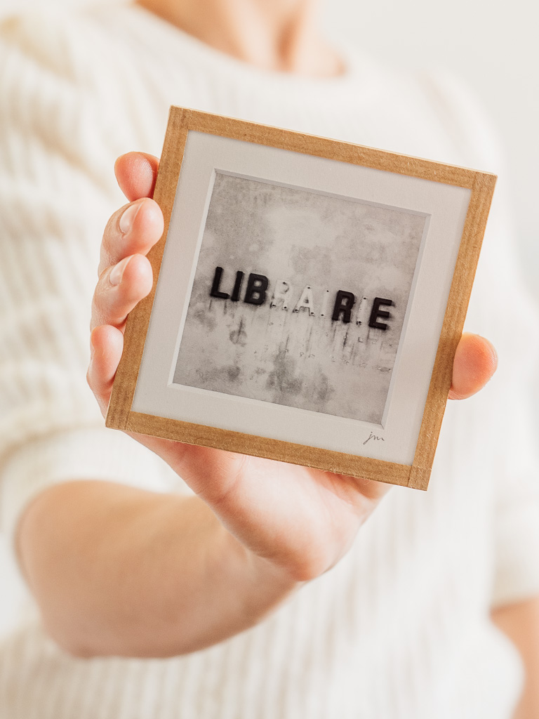 tirage photo petit format encadré à la main représentant le mot librairie écrit sur un mur avec lettres manquantes formant le mot libre