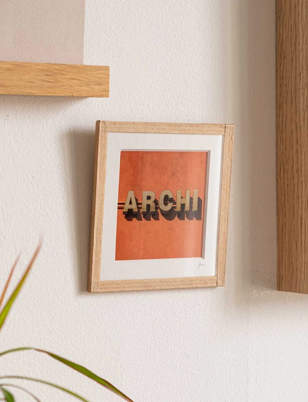 tirage photo petit format encadré à la main représentant le mot ARCHI sur mur orange