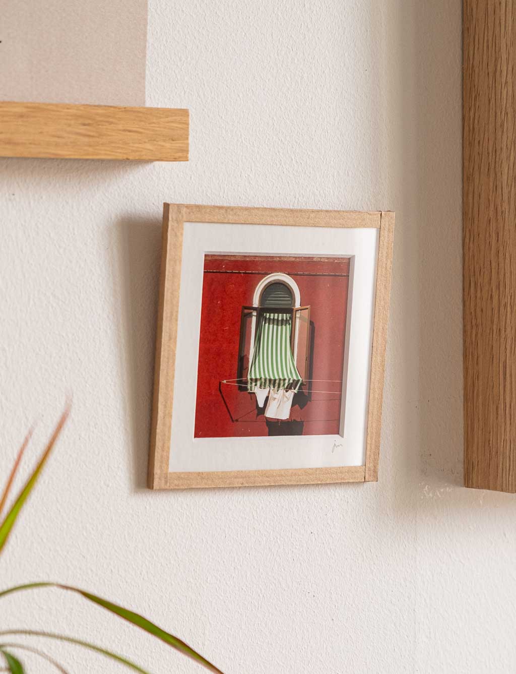 tirage photo petit format encadré à la main représentant une fenêtre avec un store rayé vert et linge qui sèche