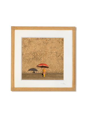 tirage photo petit format encadré à la main représentant une femme en bottes jaune assise sous un grand parasol rouge