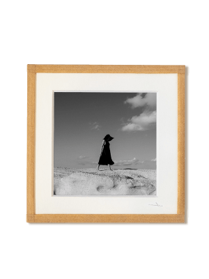 tirage photo petit format encadré à la main représentant une femme en robe noir marchant sur les roches blanches de Milos