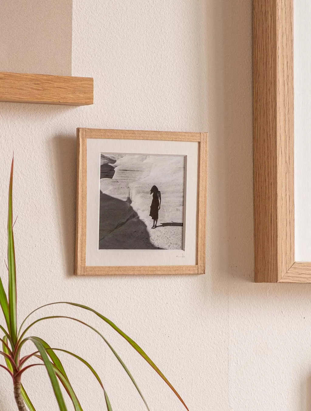 tirage photo petit format encadré à la main représentant une femme en robe noir posant sur les rochers blancs de Milos