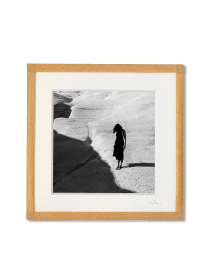 tirage photo petit format encadré à la main représentant une femme en robe noir posant sur les rochers blancs de Milos