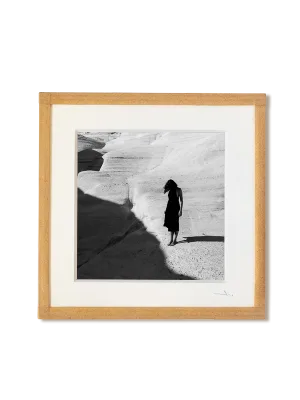 tirage photo petit format encadré à la main représentant une femme en robe noir posant sur les rochers blancs de Milos