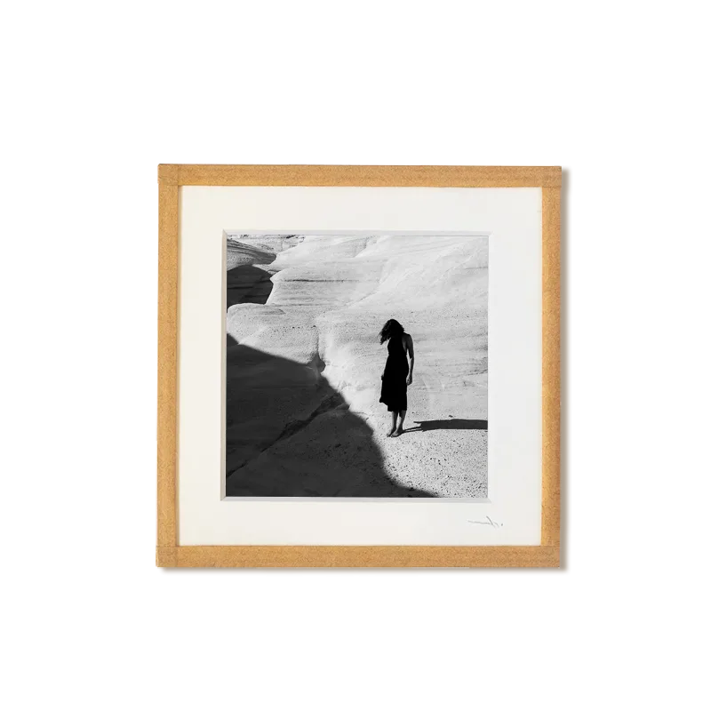 tirage photo petit format encadré à la main représentant une femme en robe noir posant sur les rochers blancs de Milos