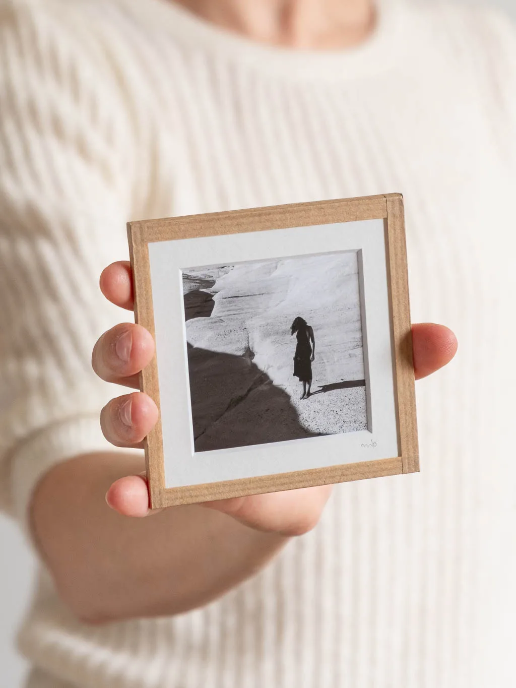 tirage photo petit format encadré à la main représentant une femme en robe noir posant sur les rochers blancs de Milos