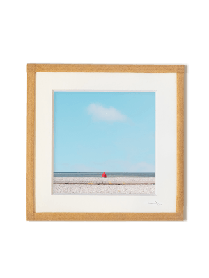 tirage photo petit format encadré à la main représentant un petit personnage rouge assis face à l'océan avec ciel bleu et un nuage