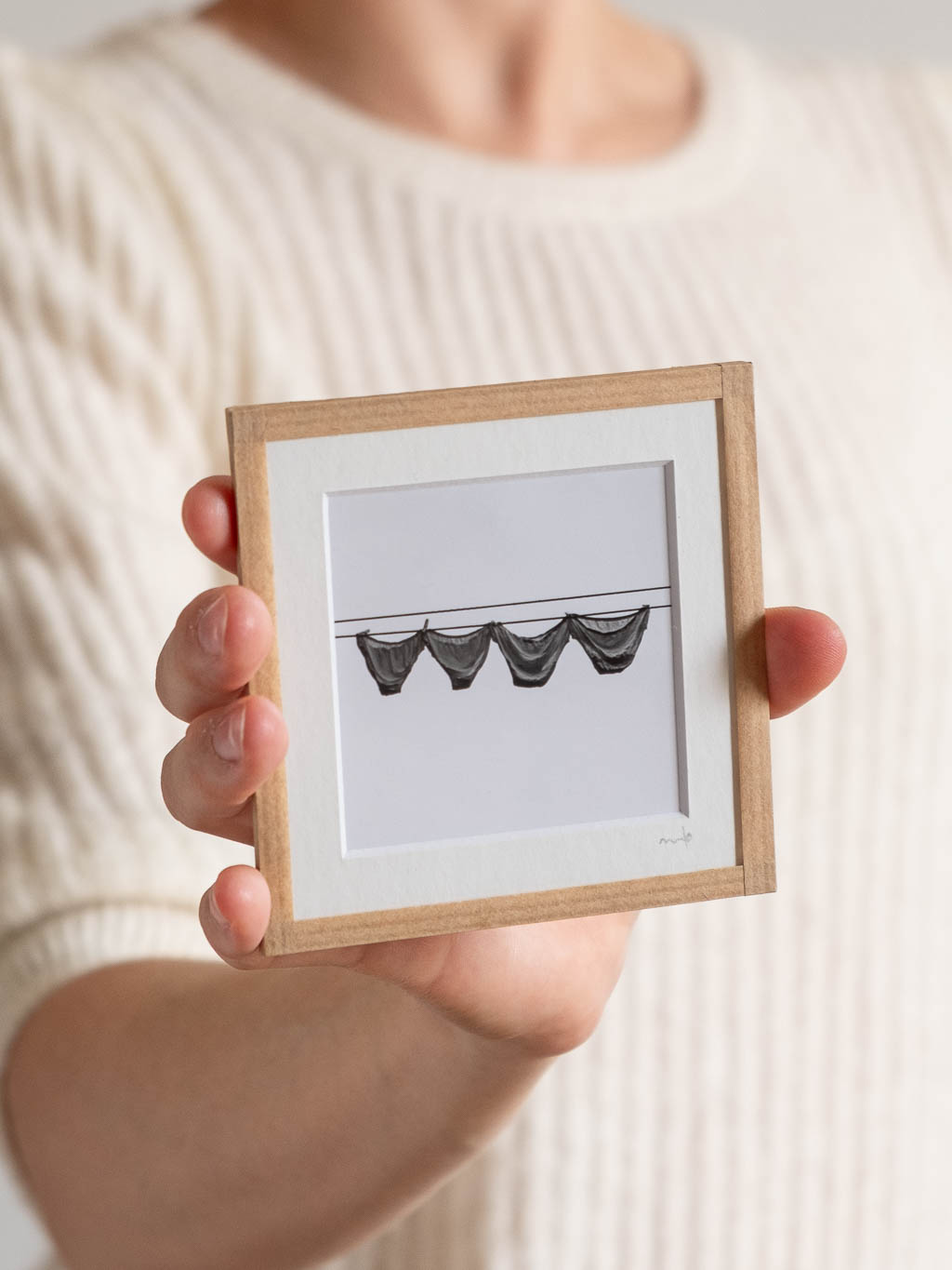 tirage photo petit format encadré à la main représentant des culottes qui sèchent sur un fil devant un mur blanc