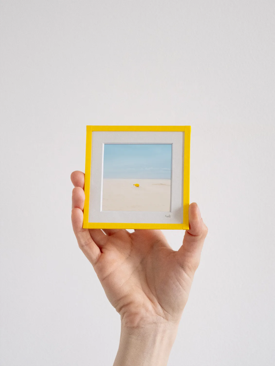 tirage photo petit format encadré à la main représentant une bouée de mouillage jaune sur le sable