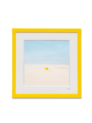 tirage photo petit format encadré à la main représentant une bouée de mouillage jaune sur le sable