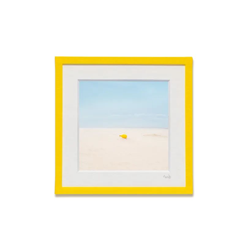tirage photo petit format encadré à la main représentant une bouée de mouillage jaune sur le sable