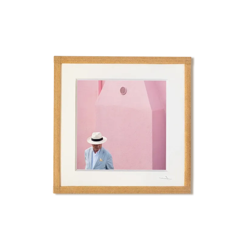 tirage photo petit format encadré à la main représentant un homme portant une chapeau Panama devant un mur rose