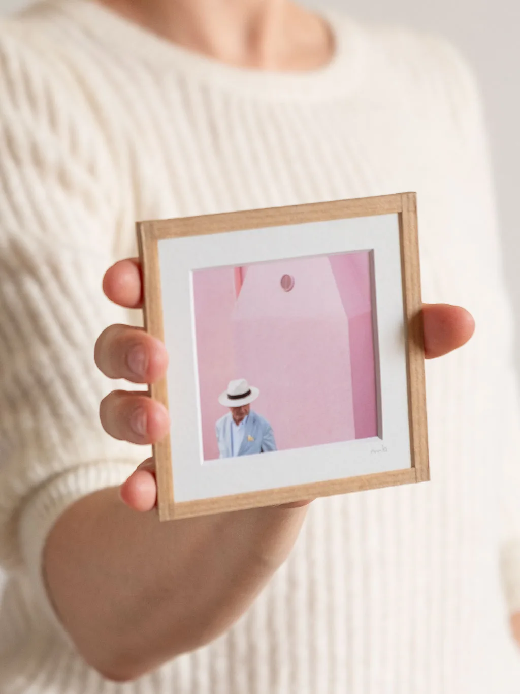 tirage photo petit format encadré à la main représentant un homme portant une chapeau Panama devant un mur rose