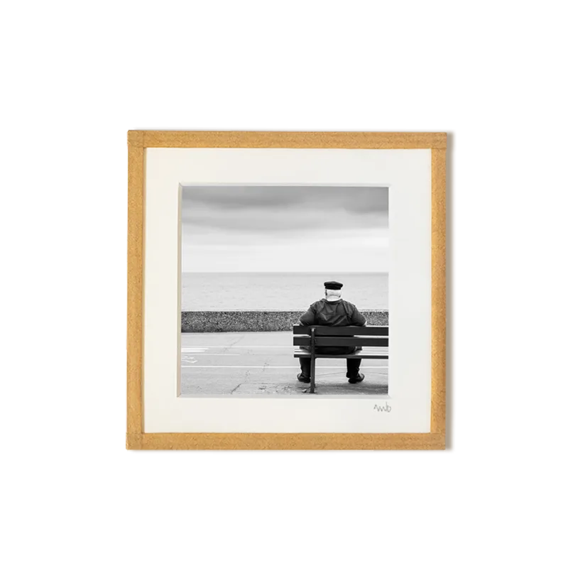 tirage photo petit format encadré à la main représentant un vieil homme au look d'un marin assis de dos sur un banc face à la mer