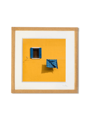tirage photo petit format encadré à la main représentant une façade jaune avec une fenetre et un torchon bleu qui seche