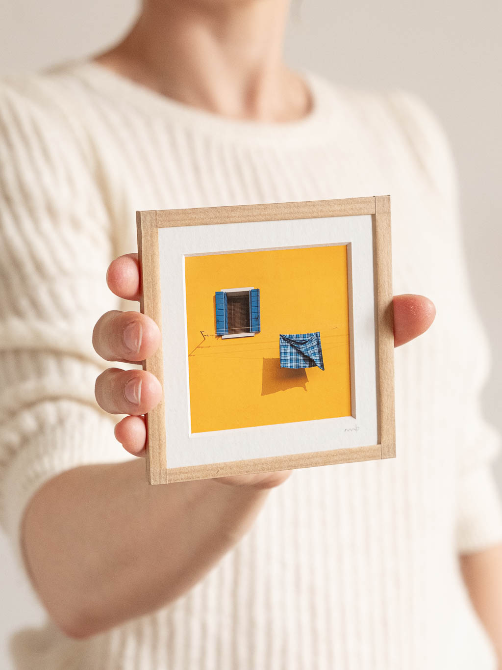 tirage photo petit format encadré à la main représentant une façade jaune avec une fenetre et un torchon bleu qui seche