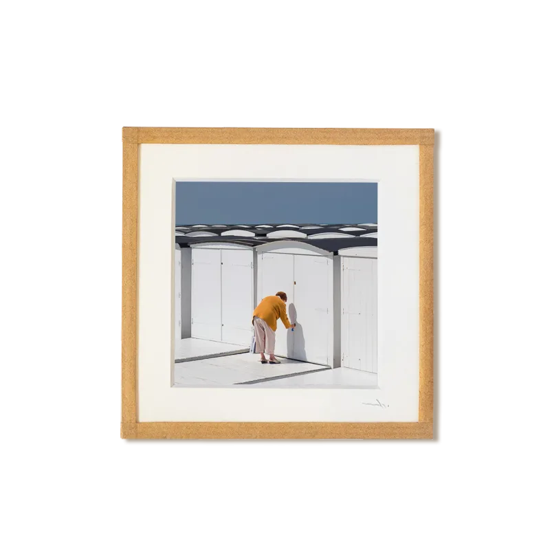 tirage photo petit format encadré à la main représentant une vieille femme de dos ouvrant sa cabines de plage au havre