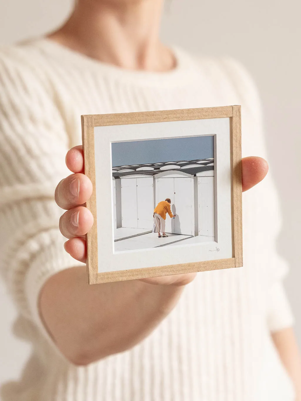 tirage photo petit format encadré à la main représentant une vieille femme de dos ouvrant sa cabines de plage au havre