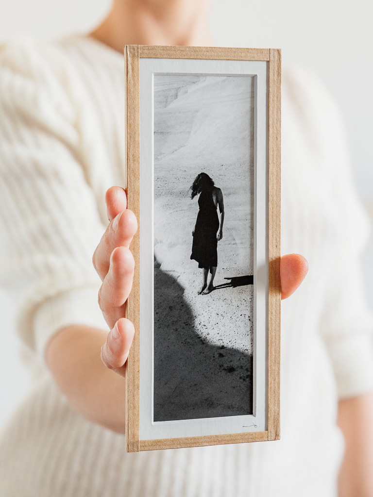 tirage photo petit format encadré à la main représentant une femme en robe noir posant dans les rochers blancs de Milos
