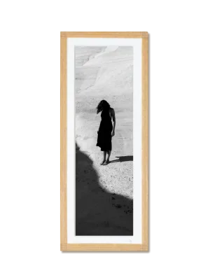 tirage photo petit format encadré à la main représentant une femme en robe noir posant dans les rochers blancs de Milos