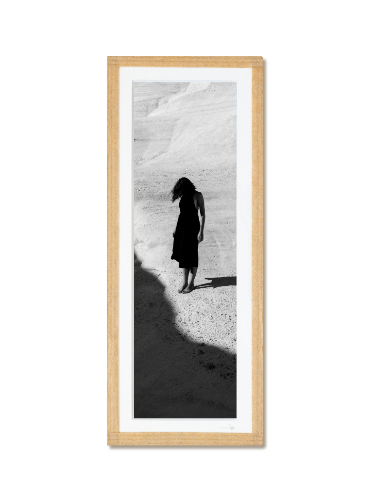 tirage photo petit format encadré à la main représentant une femme en robe noir posant dans les rochers blancs de Milos